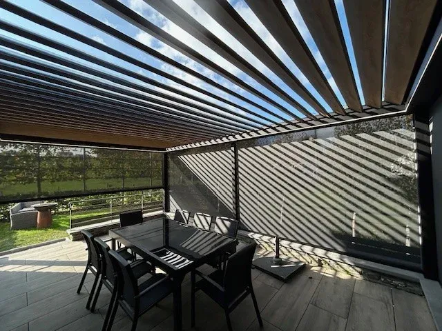 Lames orientables d’une pergola bioclimatique ouvertes au-dessus d’une terrasse meublée