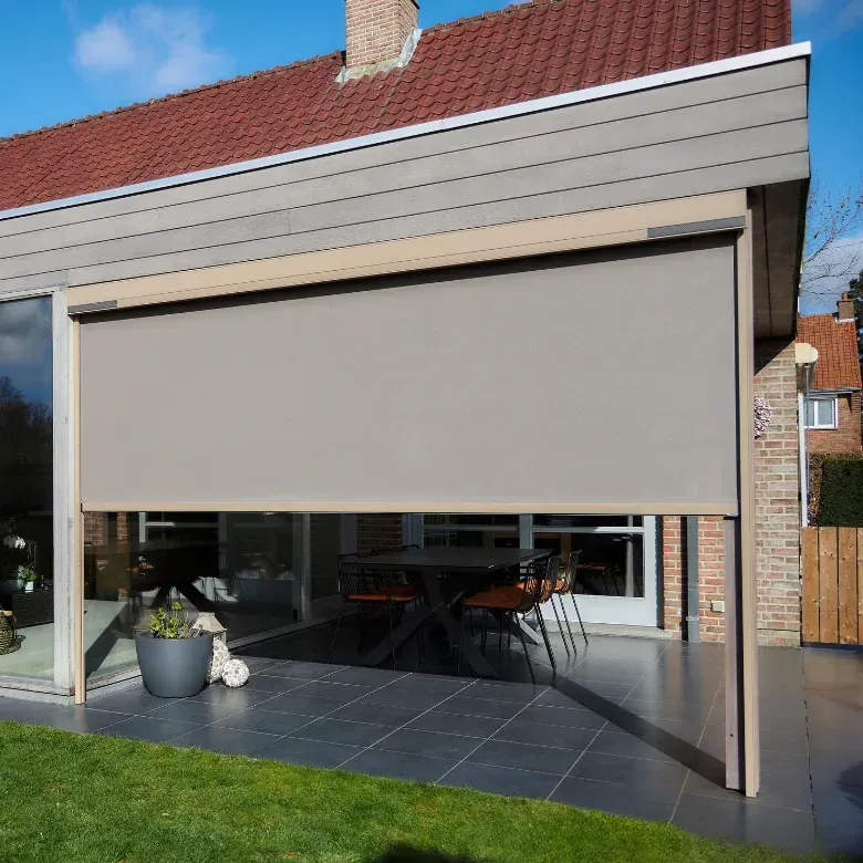 Screen vertical descendu sur la baie vitrée d’une extension, devant une terrasse carrelée