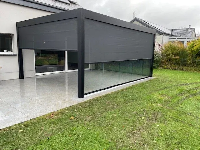 Pergola anthracite fermée par des screens et des parois vitrées coulissantes, sur une terrasse carrelée